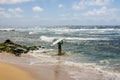 a man surfing at Sandy Beach with vast blue ocean water, rocks covered in lush green algae, crashing waves, blue sky and clouds Royalty Free Stock Photo