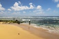 a man surfing at Sandy Beach with vast blue ocean water, rocks covered in lush green algae, crashing waves, blue sky and clouds Royalty Free Stock Photo