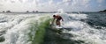 Man surfing skims the water with hand over a green wave Royalty Free Stock Photo