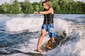 A man is surfing on a surfboard drawn by a motor boat above the wave of the boat. Weixerfer is engaged in surfing, entertainment, Royalty Free Stock Photo