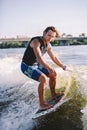 A man is surfing on a surfboard drawn by a motor boat above the wave of the boat. Weixerfer is engaged in surfing, entertainment, Royalty Free Stock Photo