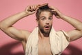 Man with surprised face, bath towel on sexy chest. Guy brush hair with hairbrush on pink background. Haircare, wellness Royalty Free Stock Photo