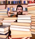 Man on surprised face holds hourglass while studying, bookshelves on background. Time flow concept. Man, scientist in Royalty Free Stock Photo