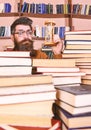 Man on surprised face holds hourglass while studying, bookshelves on background. Time flow concept. Teacher or student Royalty Free Stock Photo