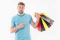 Man on surprised face pointing at shopping bags. Shopping concept. Guy holds bunch of colorful shopping bags. Man