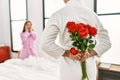 Man surprising his girlfriend with bouquet of roses at bedroom Royalty Free Stock Photo