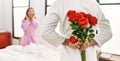 Man surprising his girlfriend with bouquet of roses at bedroom Royalty Free Stock Photo