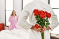 Man surprising his girlfriend with bouquet of roses at bedroom Royalty Free Stock Photo