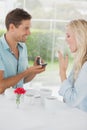 Man surprising his girlfriend with a proposal in cafe