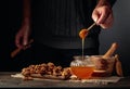 Man in a sweater prepares a breakfast of walnuts and honey