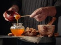 Man in a sweater prepares a breakfast of walnuts and honey