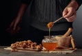 Man in a sweater prepares a breakfast of walnuts and honey