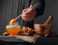 Man in a sweater prepares a breakfast of walnuts and honey