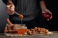 Man in a sweater prepares a breakfast of walnuts and honey