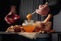 Man in a sweater prepares a breakfast of walnuts and honey