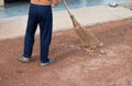 Man is sweeping the floor with the broom made from coconut leaves Royalty Free Stock Photo