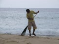 A man sweeps the beach from footprints and algae, Thailand, Phuket-October, 2012