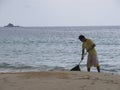 A man sweeps the beach from footprints and algae, Thailand, Phuket-October, 2012