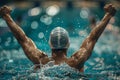 A man in a swim cap is in the water, splashing and celebrating