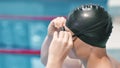 Man swimmer putting goggles on face for underwater floating in swimming pool side view