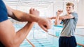 Man, swimmer and stretching with personal trainer for exercise, training or workout by indoor pool. Male person or