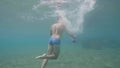 Man swimmer is training with dumbbells underwater, back view.