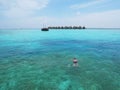 Man swimming in Maldives blue sea water near a tropical resort and traditional Maldivian boat in the background. Royalty Free Stock Photo