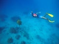 Man swimming with sea turtle. Snorkel in yellow fins swims underwater.