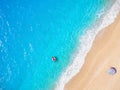 A man floats on a donut shaped inflatable over tropical, turquoise water