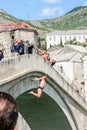 Man in a swimsuit jumping from Old Bridge of Mostar in the Neretva river during a sunny afternoon.