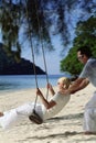 Man swinging woman on swing at beach Royalty Free Stock Photo