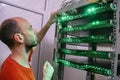 A man switches the wires in the computer equipment. Portrait of a technician in the server room of a data center. The technician Royalty Free Stock Photo