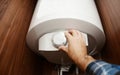 A man is switching on a domestic electric hot water boiler water heater in a bathroom cabinet setting the temperature of the hot