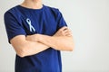 Man with symbolic blue ribbon on light background. Prostate cancer concept