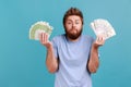 Man in T-shirt holding fans of dollar and euro banknotes, currency exchange rates, payment service. Royalty Free Stock Photo