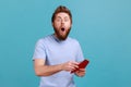 Man in T-shirt reading letter or greeting card, holding envelope, being astonished of shocked news. Royalty Free Stock Photo