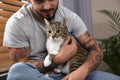 Man with tabby cat near window, closeup. Friendly pet