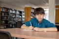 a man at a table in a library writing something on a piece of paper Royalty Free Stock Photo