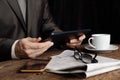 The man at the table works on the tablet. Nearby is a cup of black coffee, a newspaper, glasses and a mobile phone. Work in the Royalty Free Stock Photo