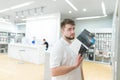 Man with a tablet case stands in a technology store and looks at the camera. Buy gadget accessories in a modern store