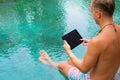 Man with tablet computer by the pool