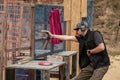 Man in tactical clothes shooting from a pistol, reloading the gun and aiming at the target in the open-door Shooting range.