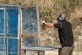 Man in tactical clothes shooting from a pistol, reloading the gun and aiming at the target in the open-door Shooting range. Royalty Free Stock Photo