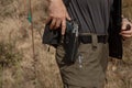 Man in tactical clothes shooting from a pistol, reloading the gun and aiming at the target in the open-door Shooting range.