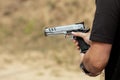 Man in tactical clothes shooting from a pistol, reloading the gun and aiming at the target in the open-door Shooting range.