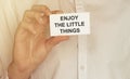 Man take a paper with text Enjoy the little things on the shirt Royalty Free Stock Photo