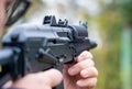 Man takes aim from an assault rifle side view close-up against the background of the forest Royalty Free Stock Photo