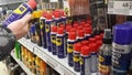Man takes a bottle of WD-40 lubricant from the store shelf, puts it back in place. Product selection in the automotive department,