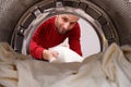 A man takes clean bed linen out of the drum of the washing machine. A concept to illustrate a bachelor or gender equality in Royalty Free Stock Photo