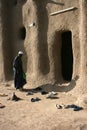 A man takes off his shoes at the entrance to a traditional mud-brick mosque in a village near Djenne, Mali Royalty Free Stock Photo